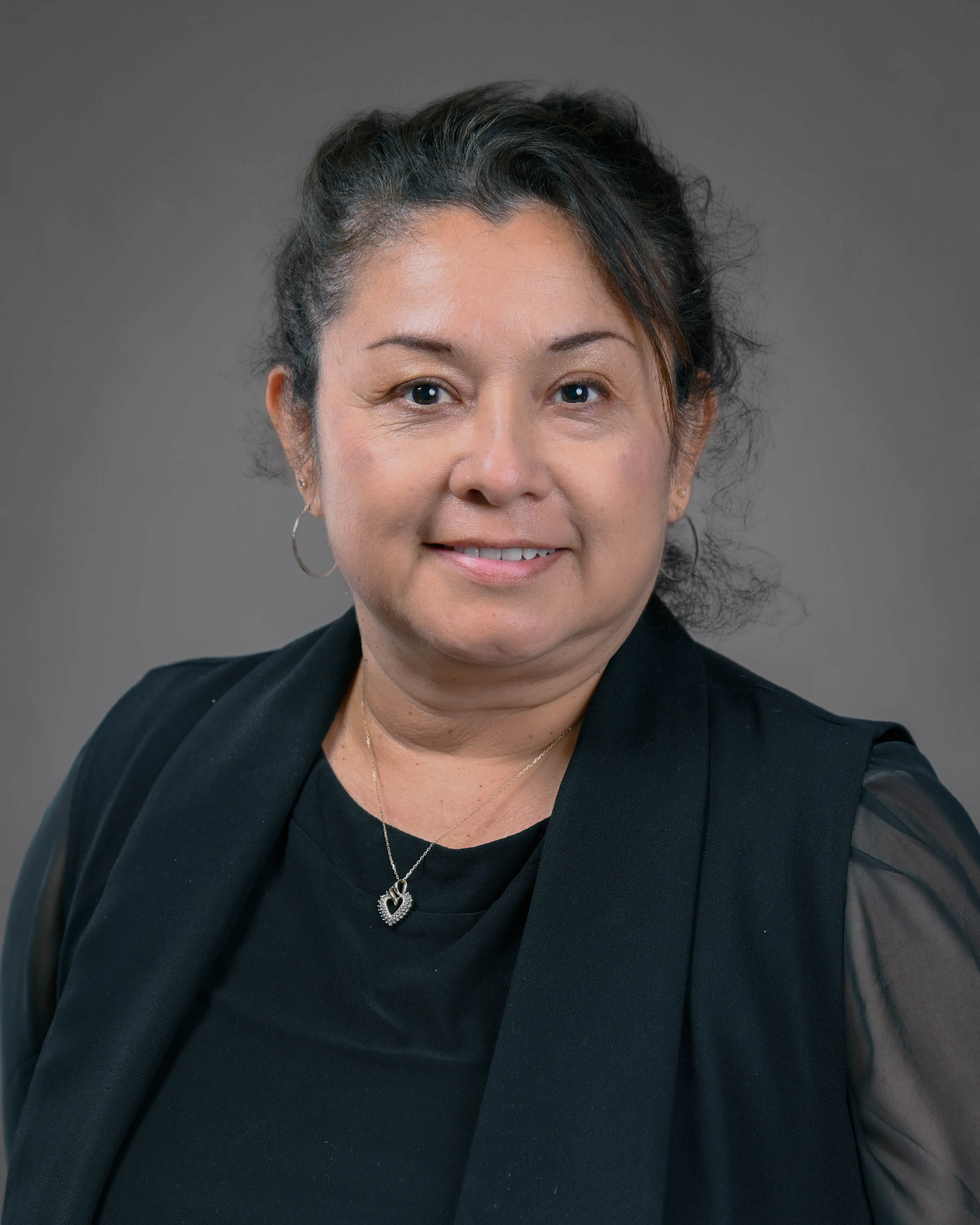 Woman in black smiling with her hair pulled up.